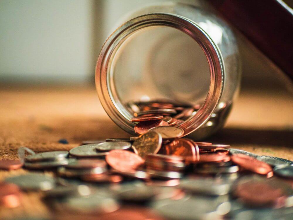 A tipped over jar with coins 