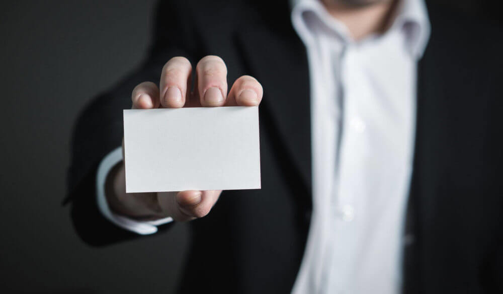 A man in a suit holding a business card