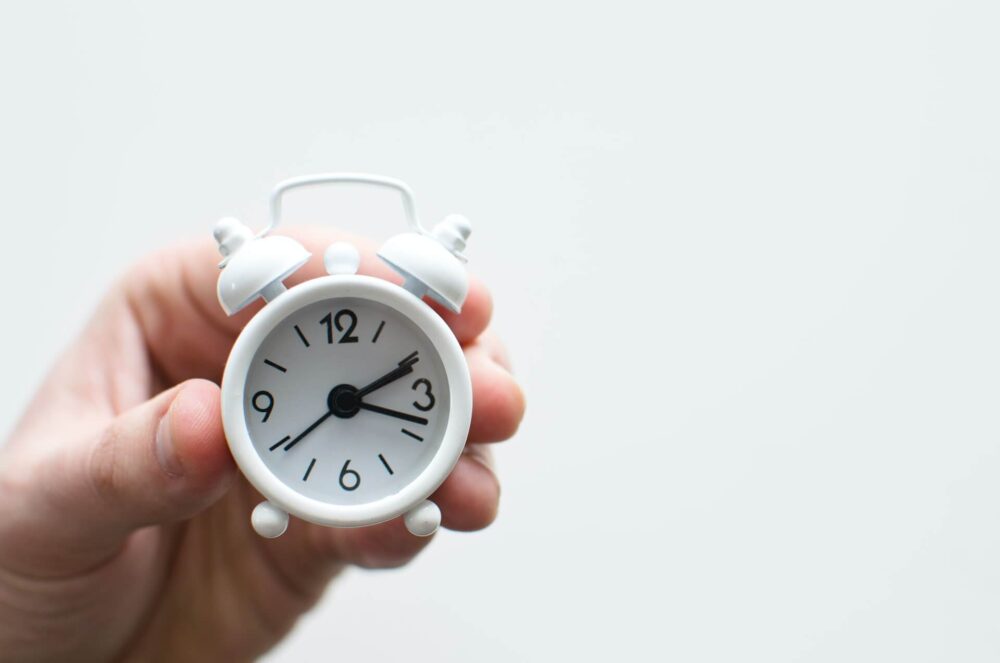 A person holding a small clock