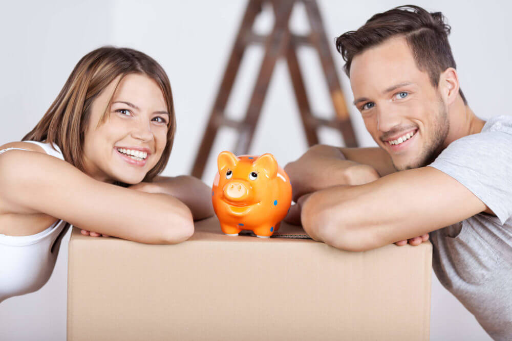 couple leaning on a box with a piggy bank on it