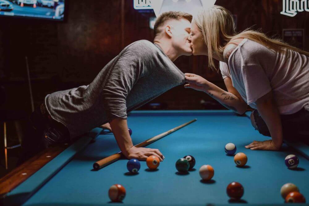 couple kissing over a pool table