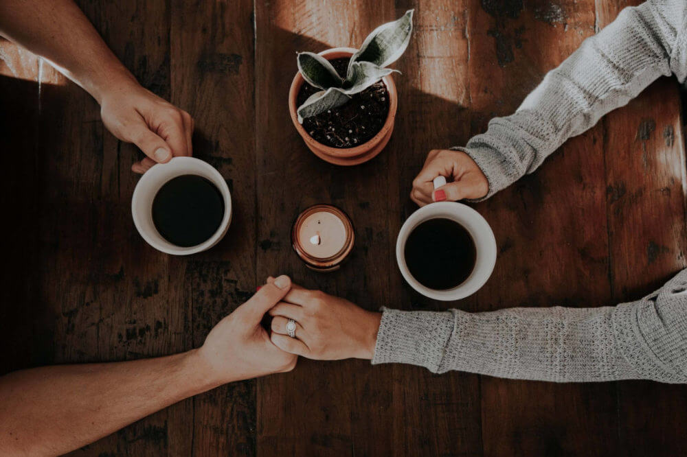couple holding hands while drinking coffee