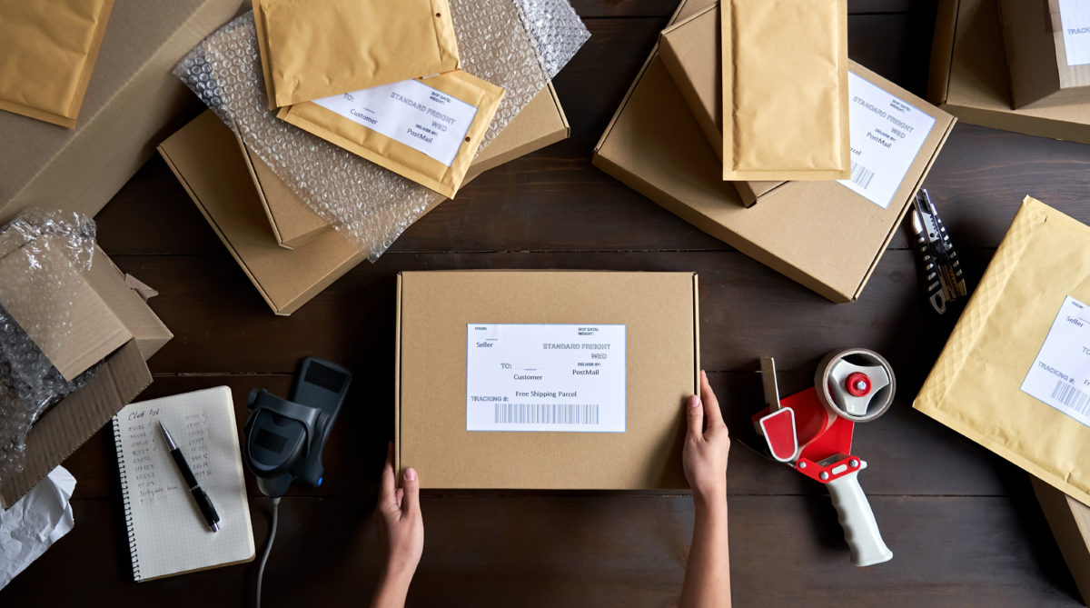 Top view of female warehouse worker packing shipping order box for dispatching.