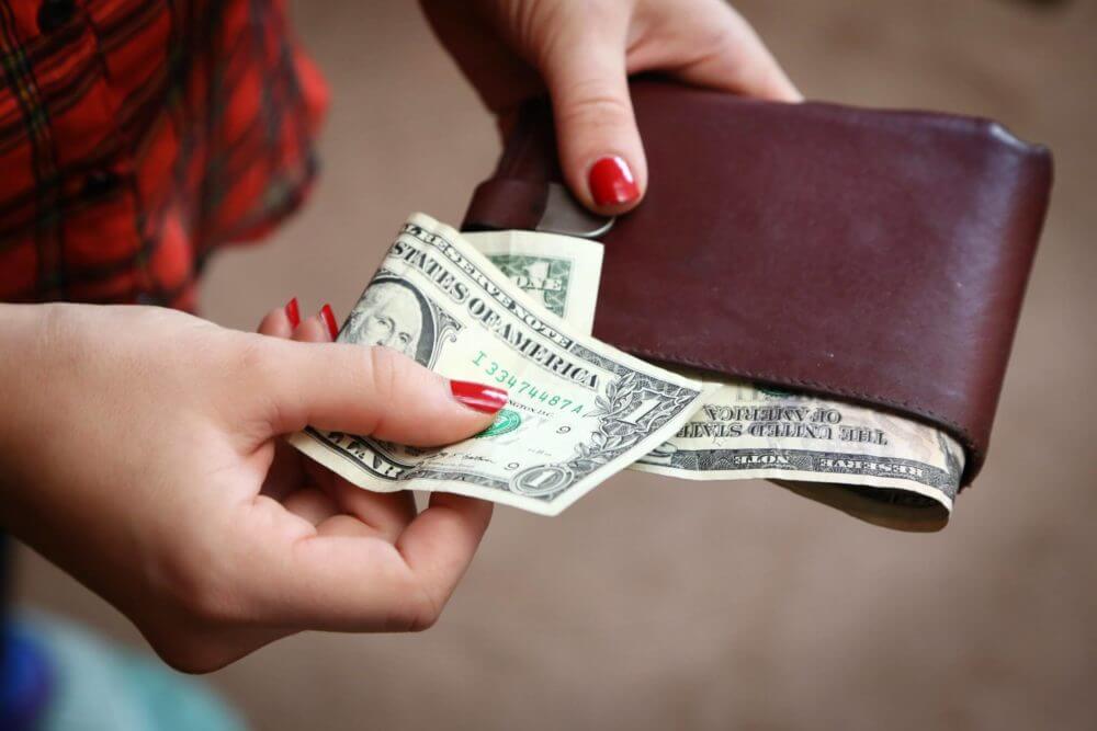 person holding a wallet filled with money