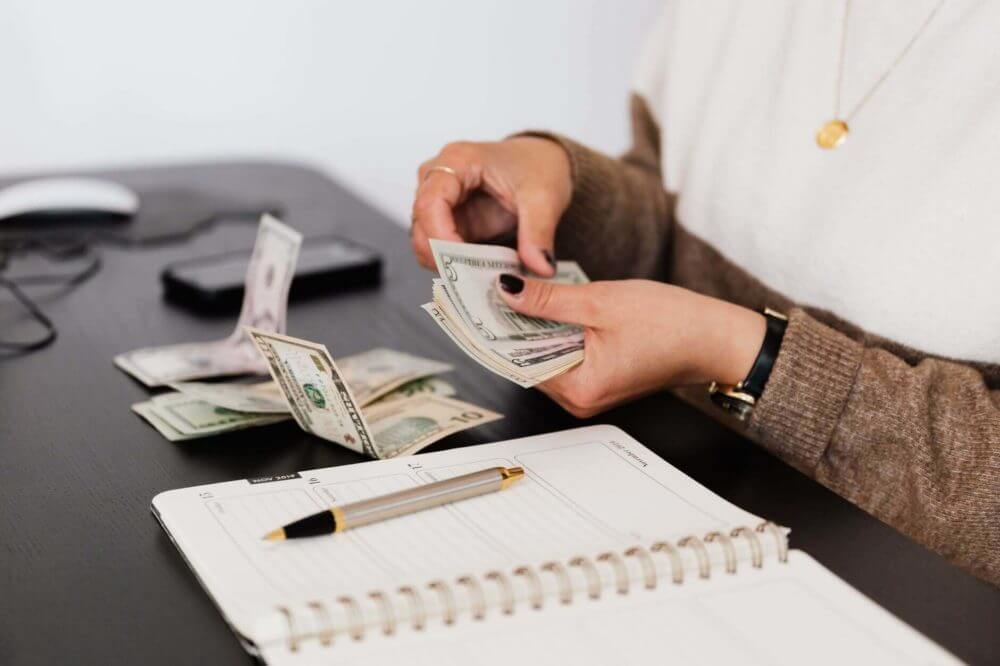 A woman counting money she’ll spend for hiring a long-distance moving company