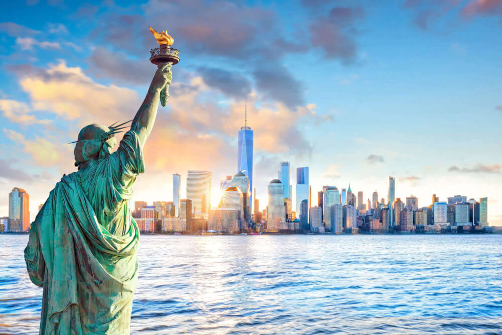 A cityscape of NYC with the Statue of Liberty in the front