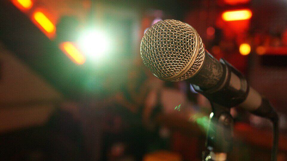 A lone microphone on stage at a comedy club