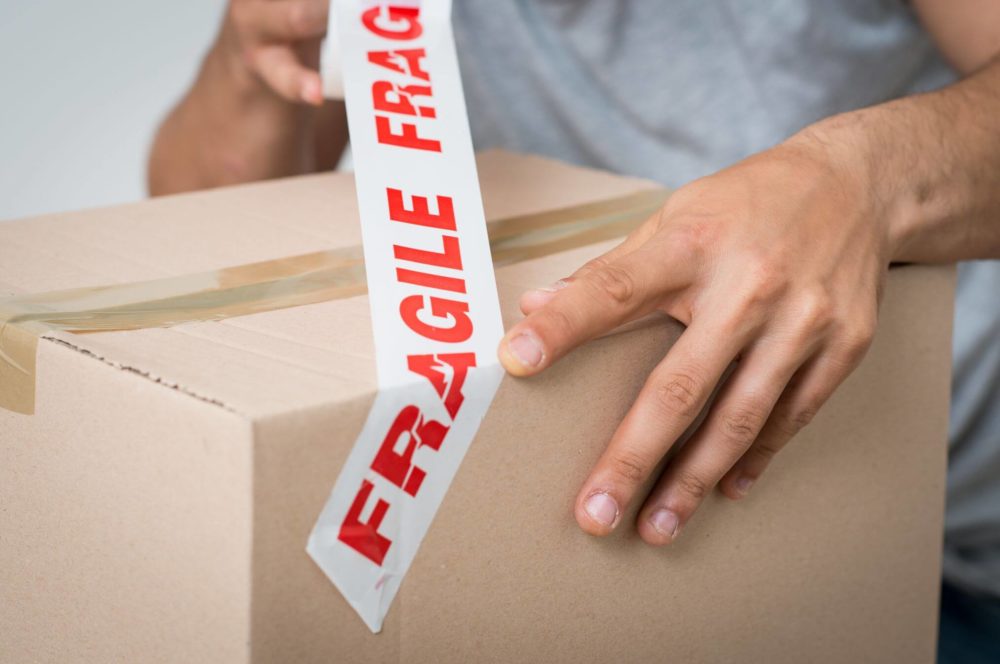 A man labeling a box as fragile with a label