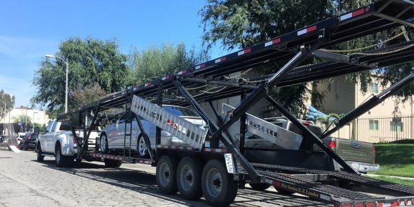 Long-distance movers shipping cars on an open trailer