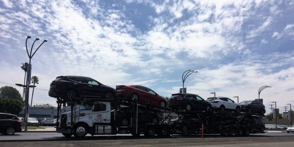 Long-distance movers shipping cars on an open trailer