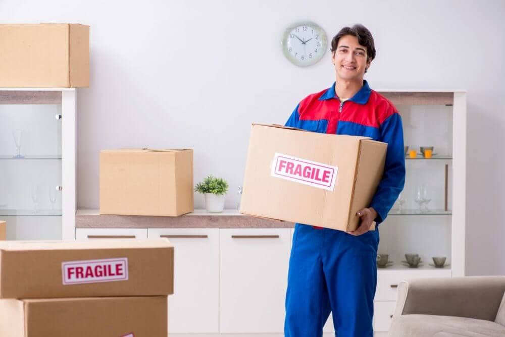 Professional mover holding a box labeled fragile