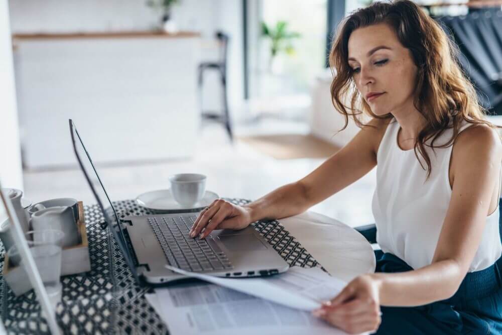 A woman with a laptop looking at papers