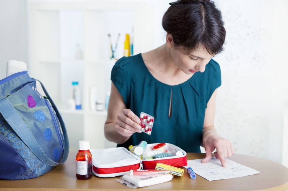 Woman putting medicine in a first aid kit