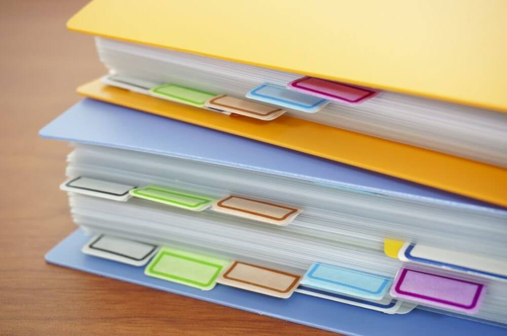 A yellow binder on top of a blue binder sitting on a table