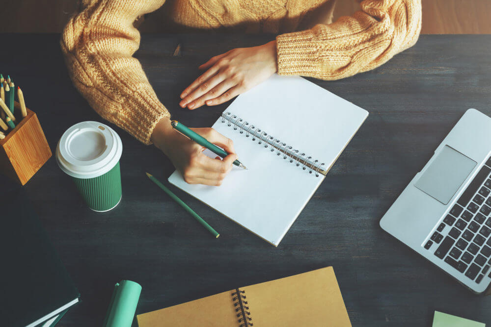 A person writing in the notebook before long-distance moving 