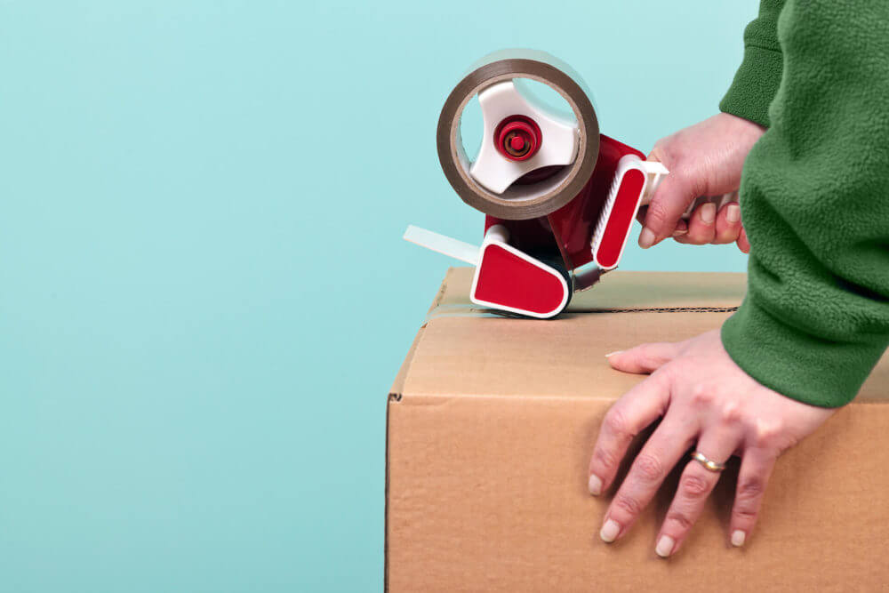 A person sealing a box with tape