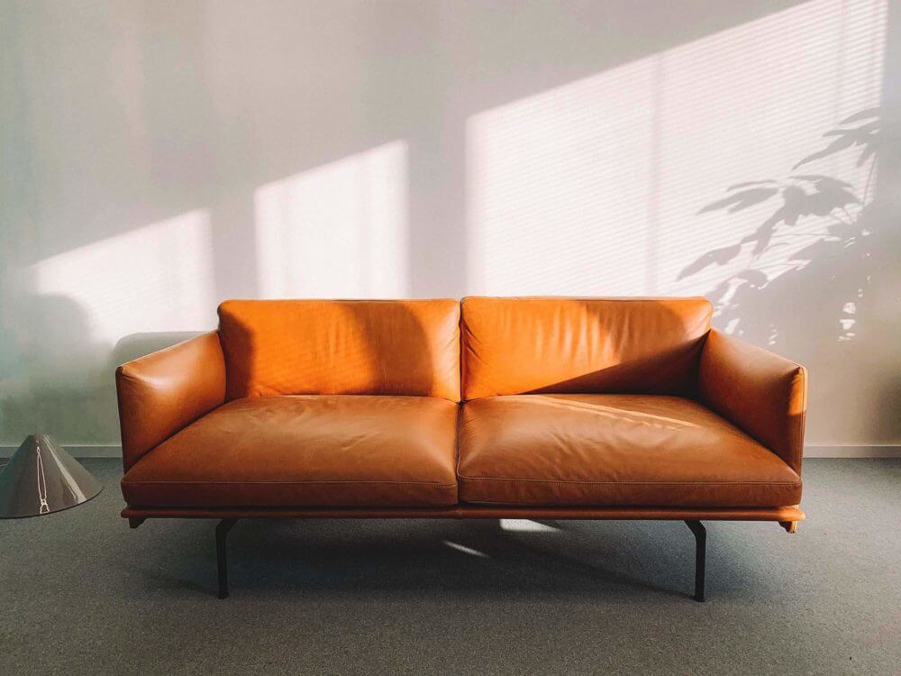 an orange leather sofa in front of a white wall