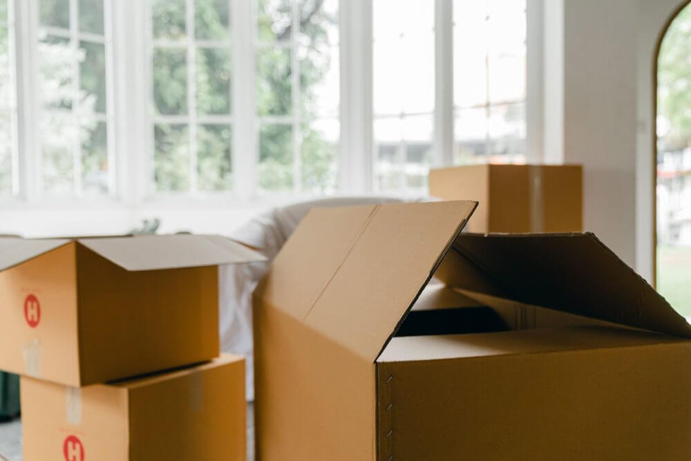 A woman with the headphones folding clothes in a suitcase before long-distance movers come to do their services