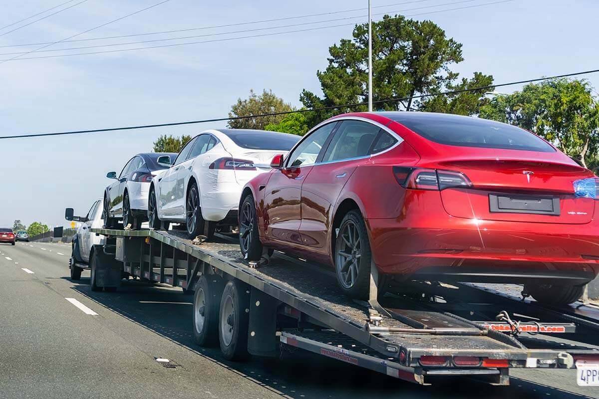 a moving truck shipping cars on an open trailer