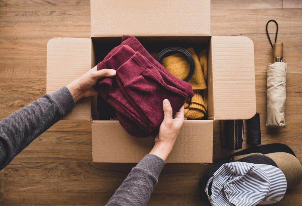 Person packing clothes into a box for long-distance moving 