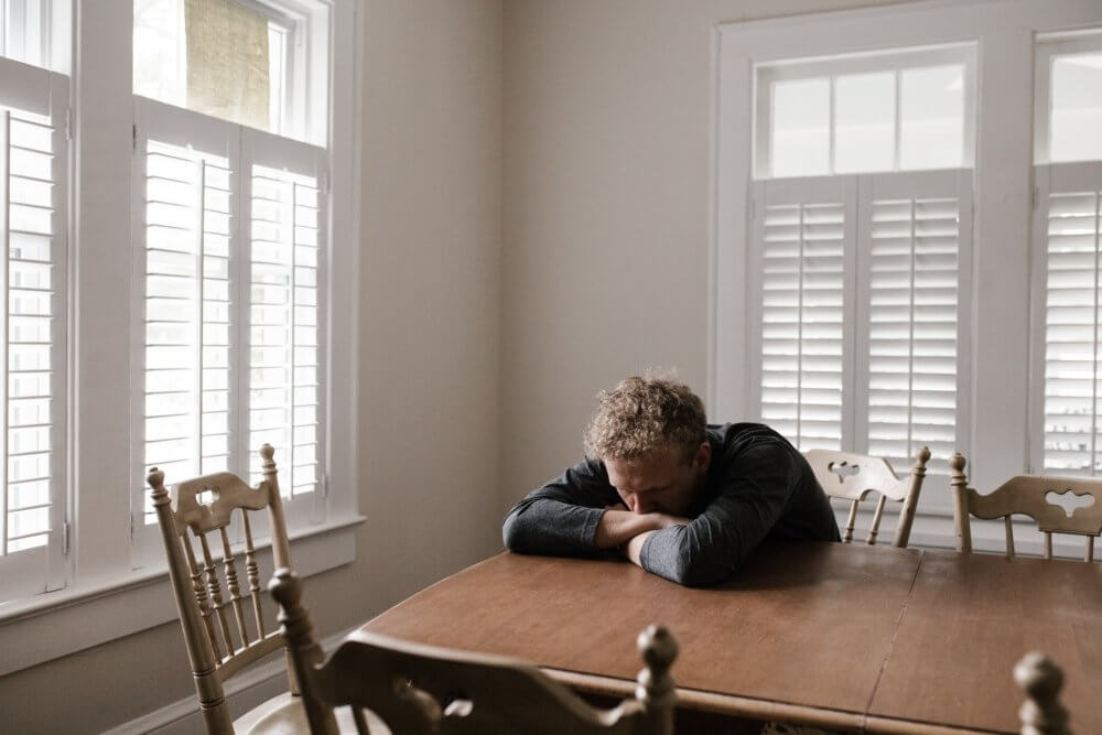 Sad man leaning on his kitchen table 