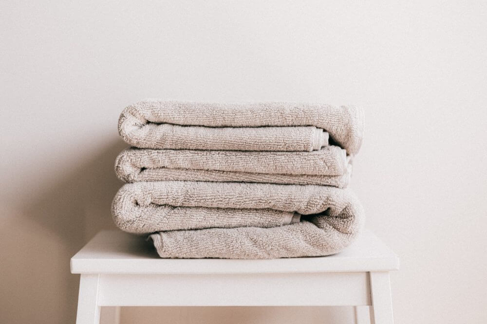 a stack of beige towels on a white stool