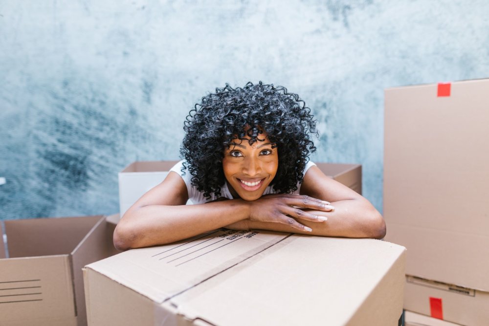 A smiling woman surrounded by boxes after cross country moving