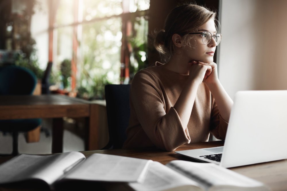 A girl in front of her laptop considering hiring a long-distance moving company