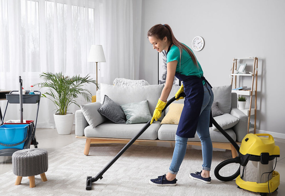 A woman vacuuming a carpet after long-distance moving services