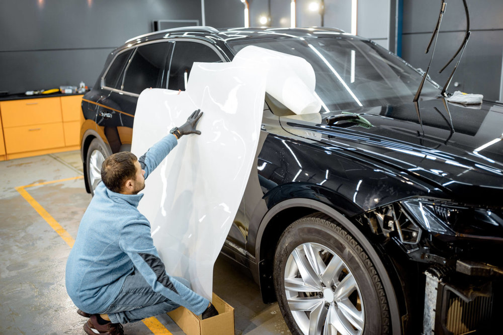 one of the cross-country movers in a long-distance moving company preparing a car for shipping