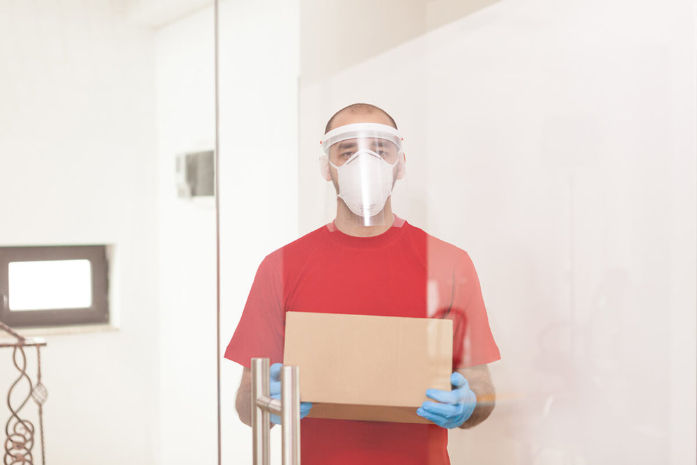 a mover from a long-distance moving company wearing protective gear and holding a box