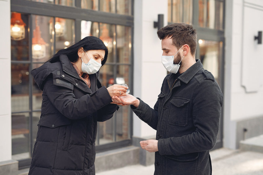 two people wearing masks and sanitizing their hands before meeting long-distance movers