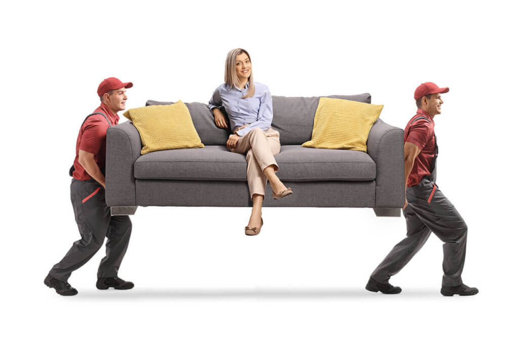 Two long-distance movers carrying a sofa on which a woman is sitting