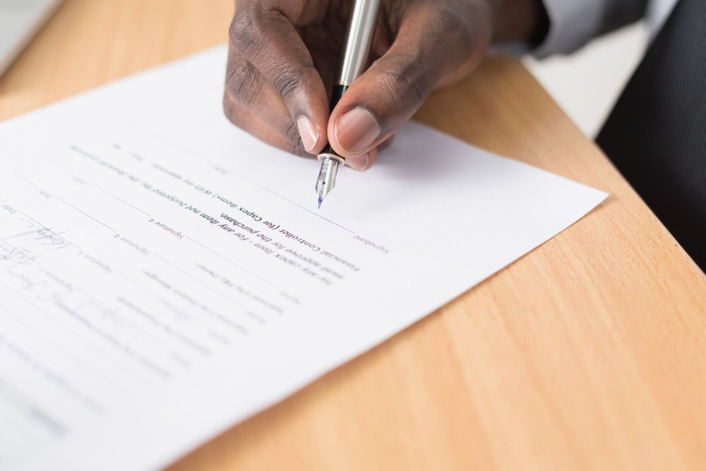 a person off-screen signing a document about renting before hiring long-distance movers