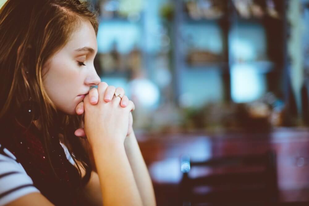 A sad woman holding her hands together close to her face