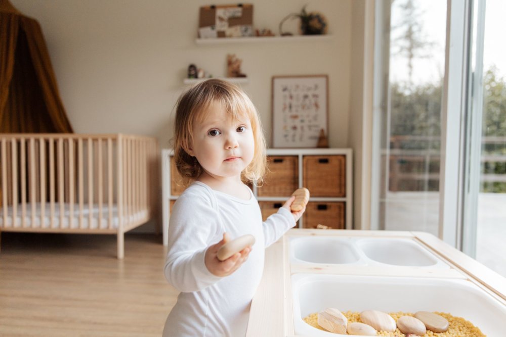 A little girl playing with a kitchen toy after long-distance movers unloaded it from the truck