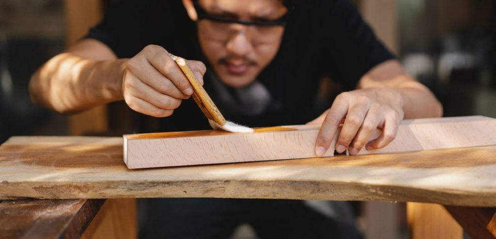 A man varnishing a wooden surface after moving cross country