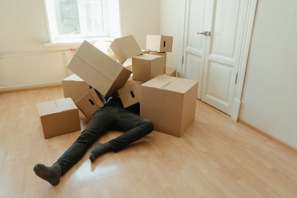 A person lying on the floor surrounded by boxes before cross-country moving 