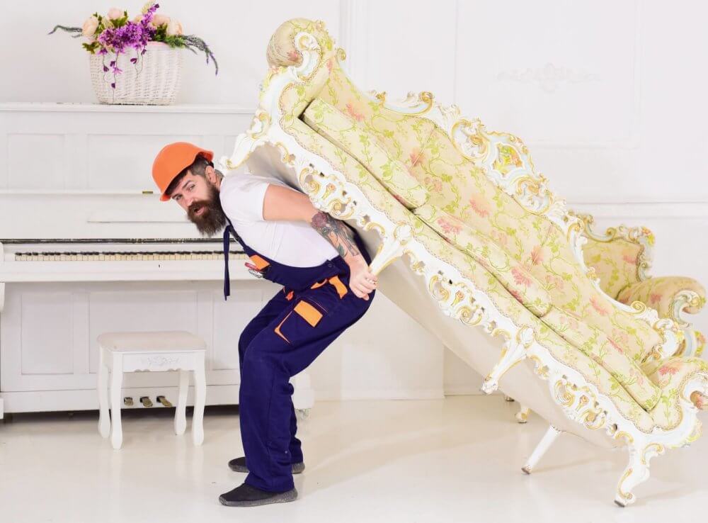 A mover lifting a sofa before cross-country moving