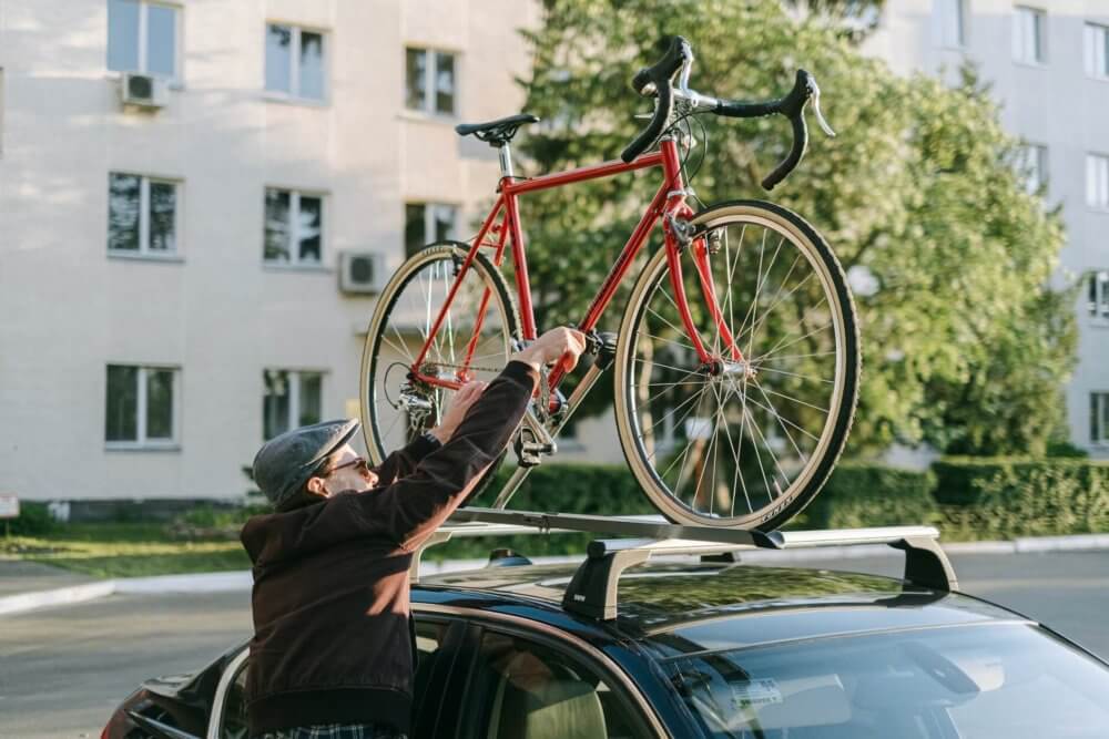 A man putting a bicycle on his car