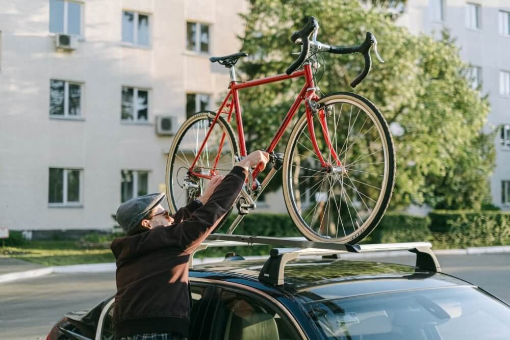 Man putting bicycle on an overhead carrier for a long-distance moving