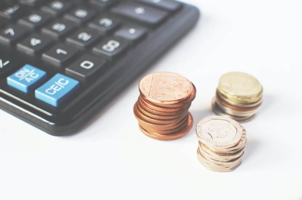 A calculator beside a pile of coins