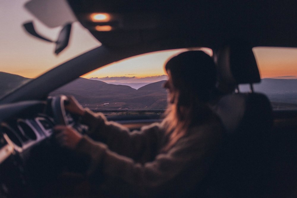 A woman driving a car in the sunset