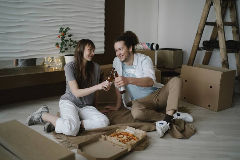 A couple eating pizza and drinking beer after cross-country moving 