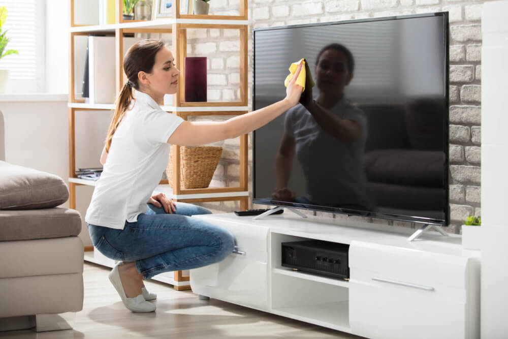 Woman cleaning a TV before long-distance moving 