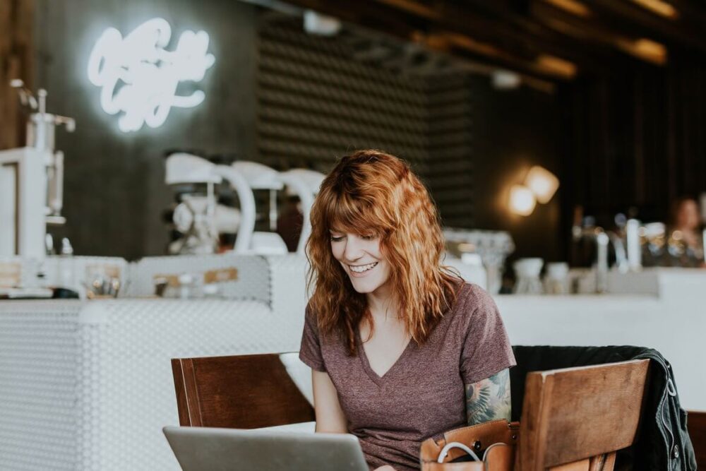 Woman sitting in a cafe, holding a laptop in her lap