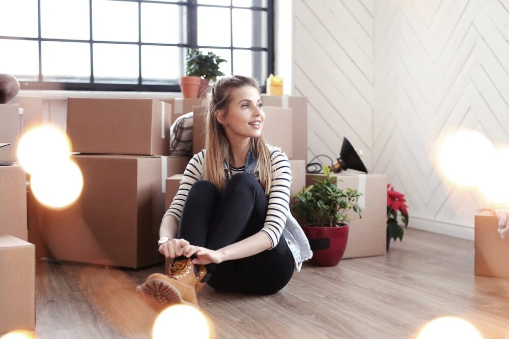 Woman sitting on the floor after cross-country moving, surrounded by boxes