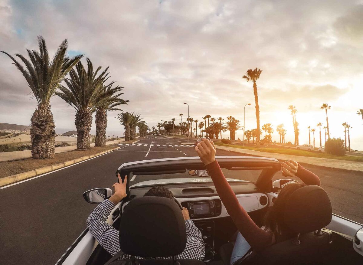 Happy people having fun in convertible car in summer vacation - Young couple laughing on cabrio auto outdoor - Travel, youth lifestyle, holidays and wanderlust concept