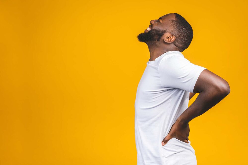 Man holding his strained back while in pain