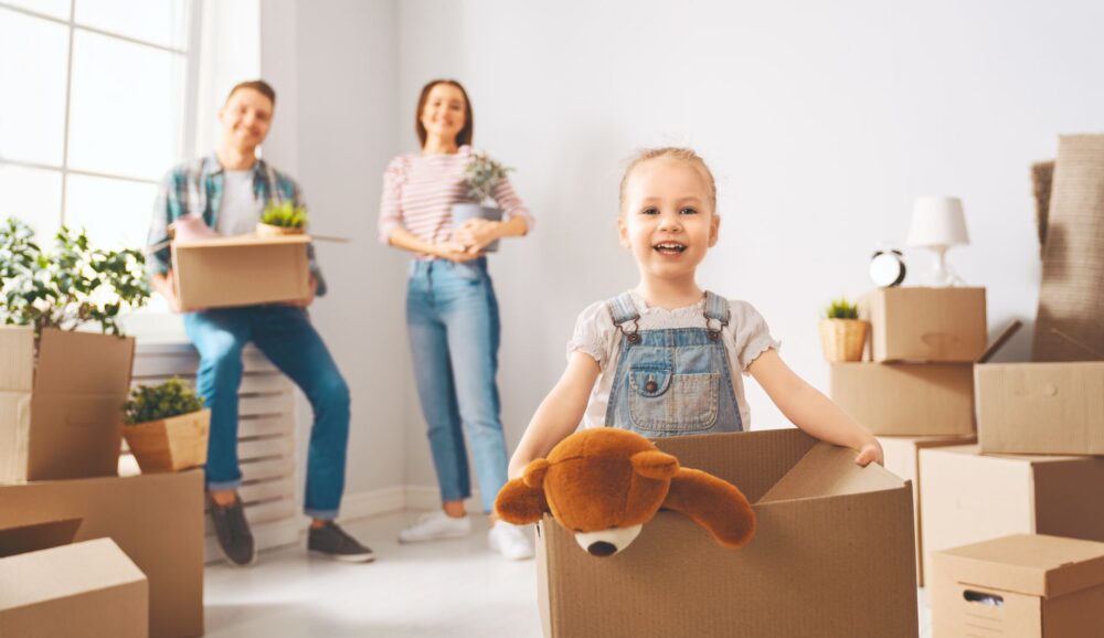 Parents and a girl smiling and carrying boxes